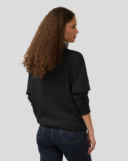 Back view of a woman wearing a black oversized Alpine dual brand quarter zip pullover.