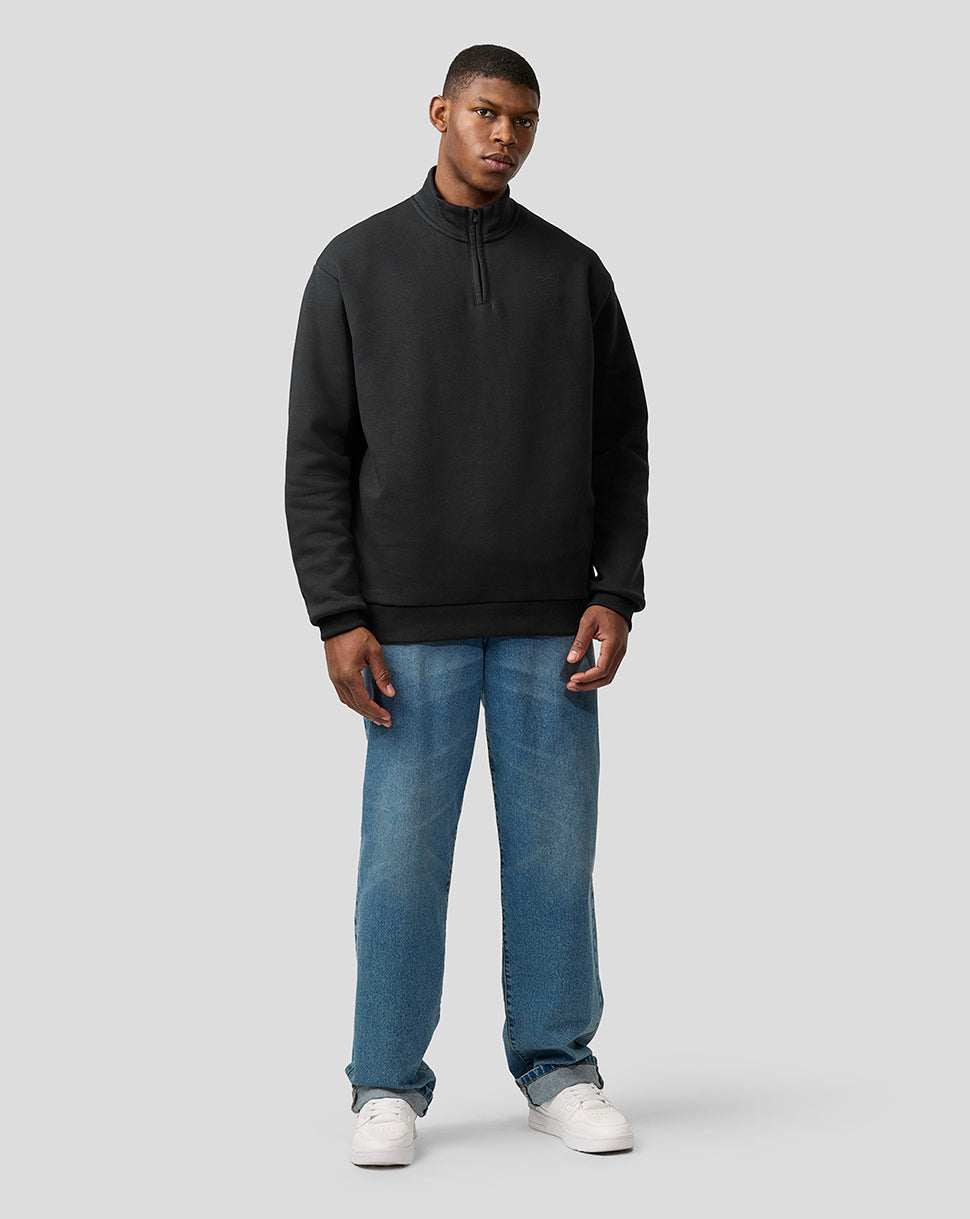 Front view of a man wearing a black quarter zip pullover with a stand up collar.