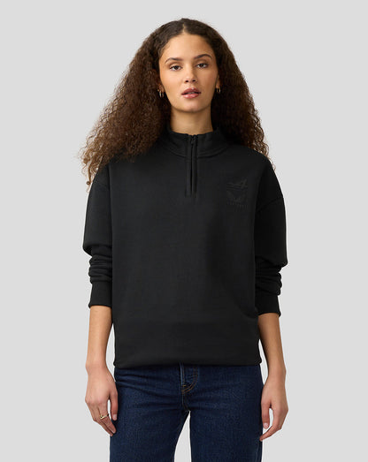 Woman wearing an oversized black pullover with a subtle Alpine Castore logo on the chest.