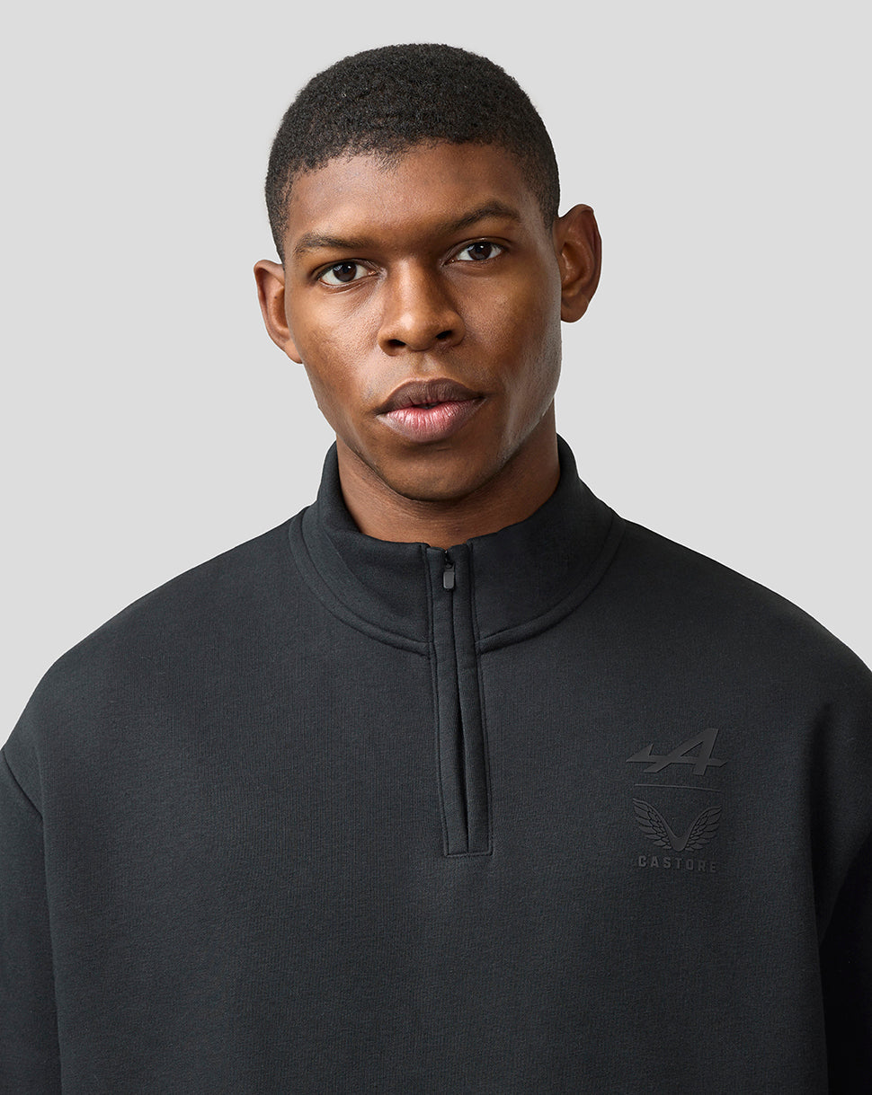 Male model wearing a black Alpine Castore unisex quarter zip pullover with funnel neckline and subtle chest branding.