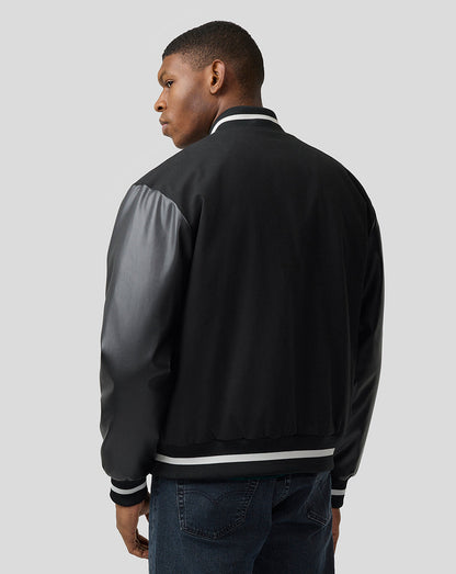 Side view of a man wearing Alpine bomber jacket with a contrasting grey leather sleeve and white striped cuffs