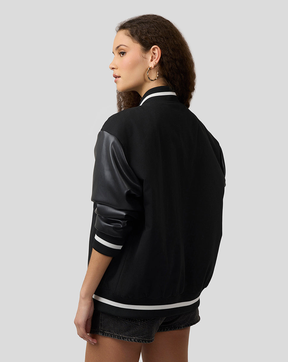 Back view of a woman wearing Alpine bomber jacket with white stripes and leather sleeve detail