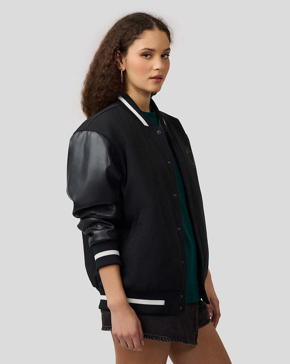 Female model wearing a black Alpine unisex bomber jacket with leather sleeves and striped cuffs.