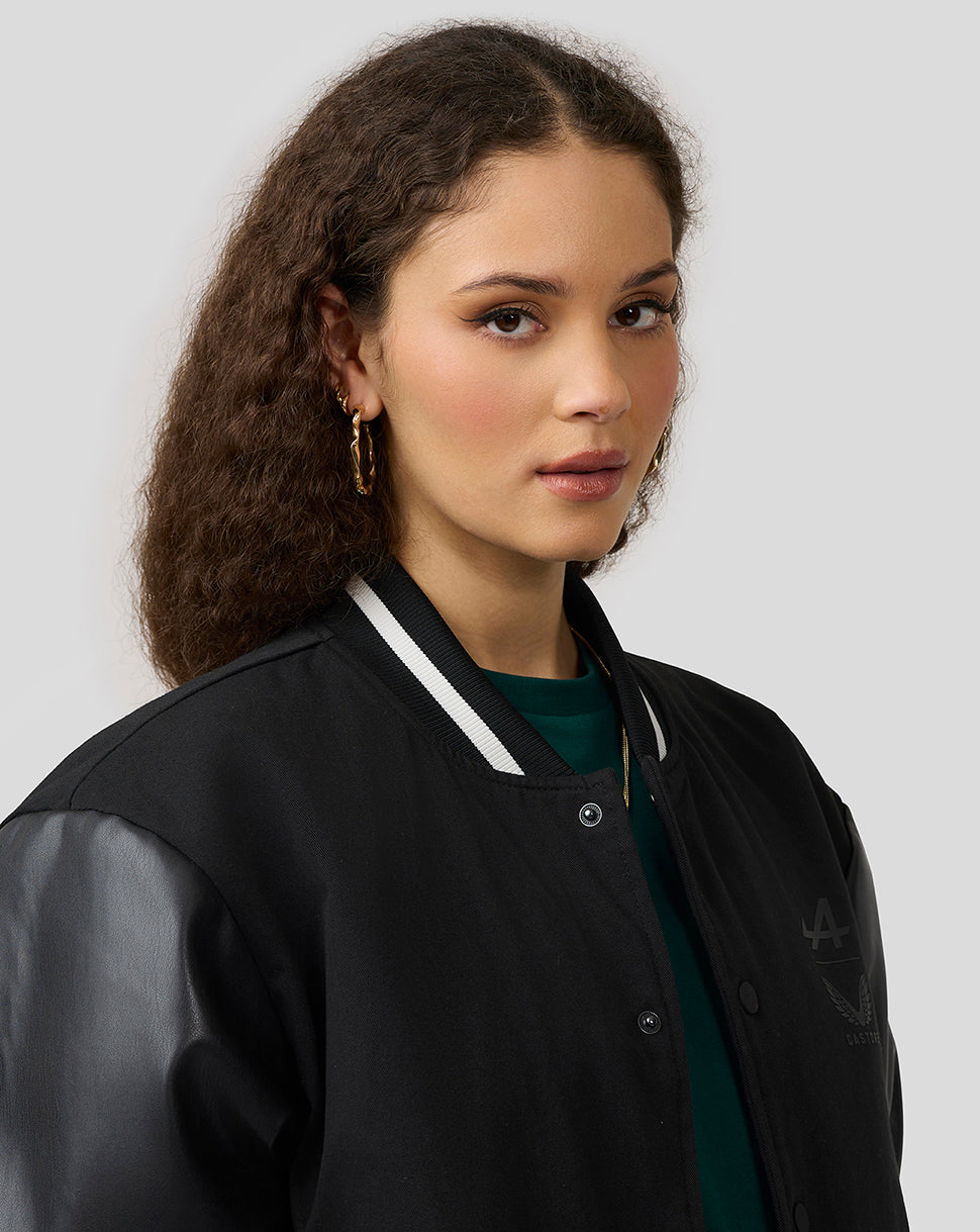 Female model wearing a black Alpine bomber jacket with leather sleeves and striped cuffs.