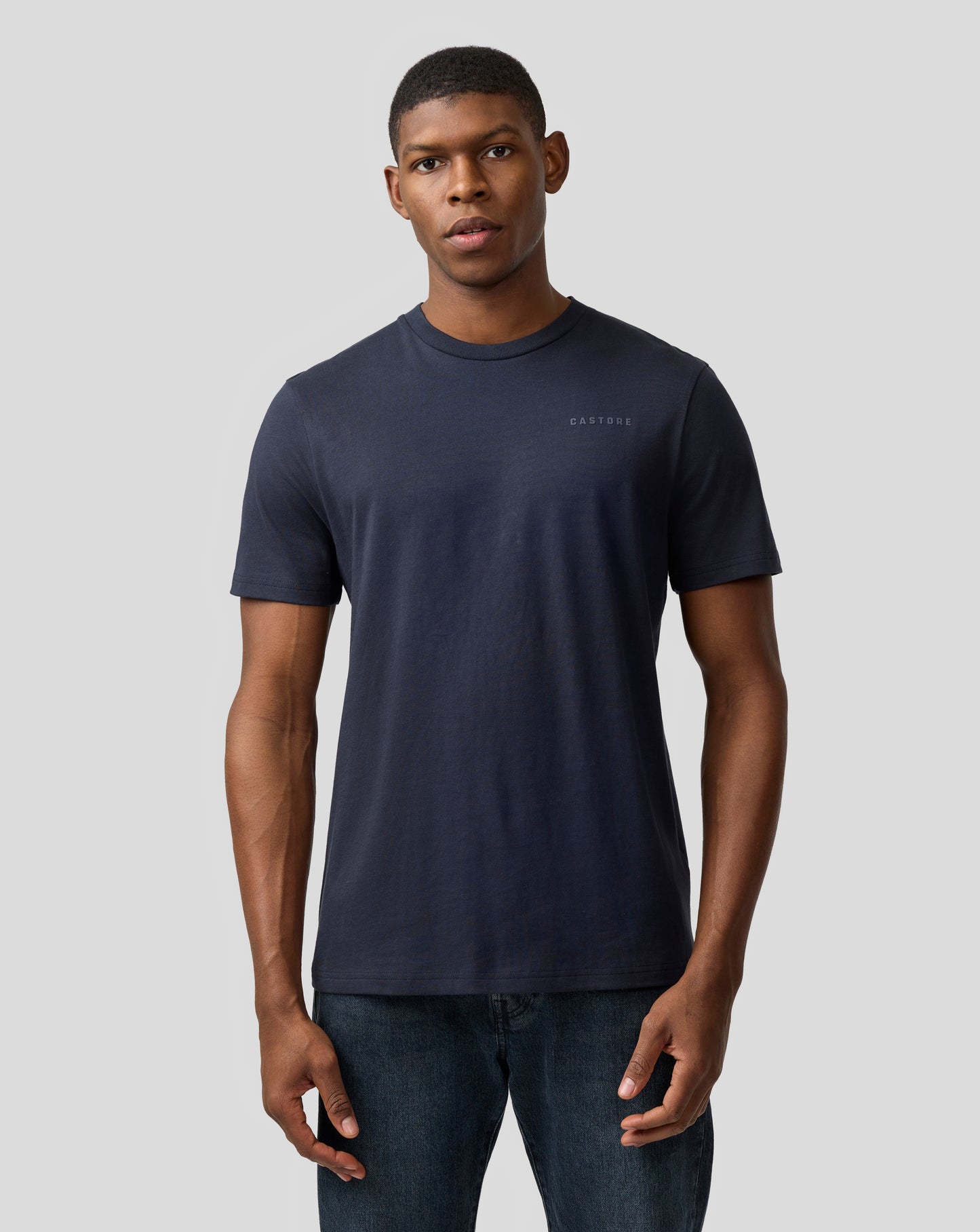 Man in a night sky navy Castore regular fit T shirt with small chest logo.