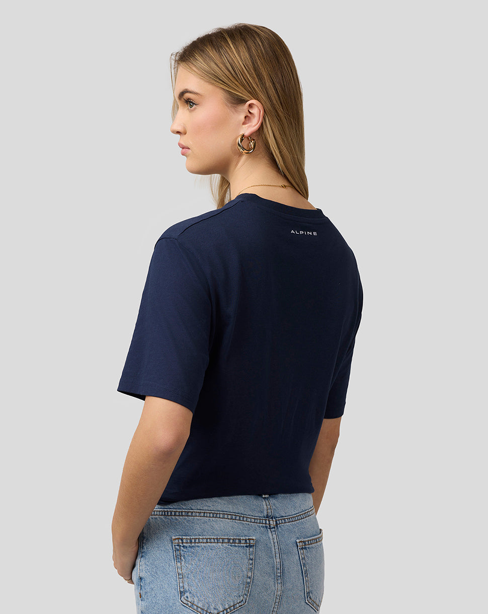 Rear view of a woman in a navy Alpine Core Essentials T-Shirt showing a small logo at the neckline.