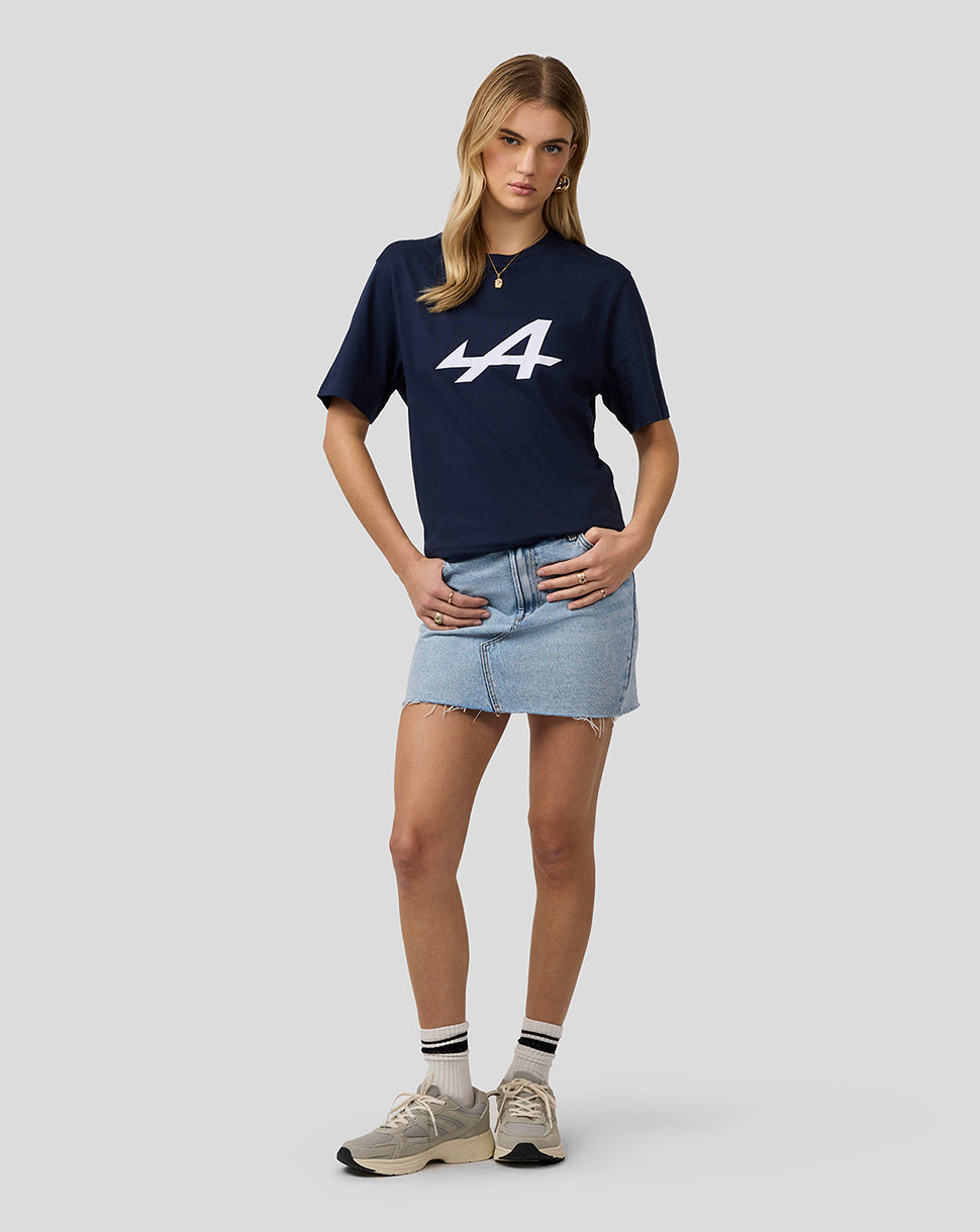 Female model in navy Alpine Core Essentials T-Shirt with large white logo, paired with a light denim mini skirt