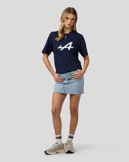Female model in navy Alpine Core Essentials T-Shirt with large white logo, paired with a light denim mini skirt