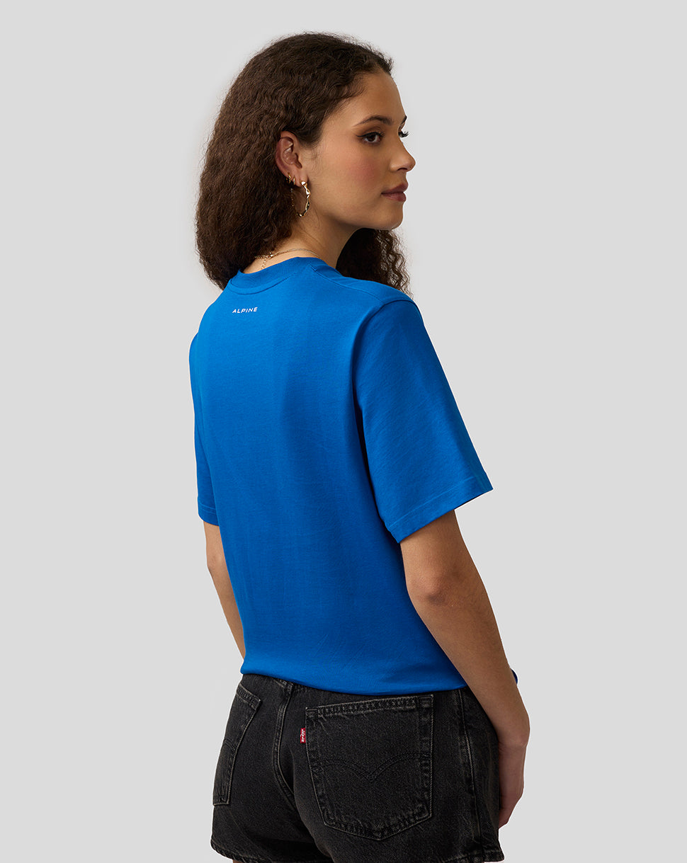 Back view of a lapis blue Alpine Core Essentials T-shirt worn by a woman, with a small Alpine logo on the upper back.