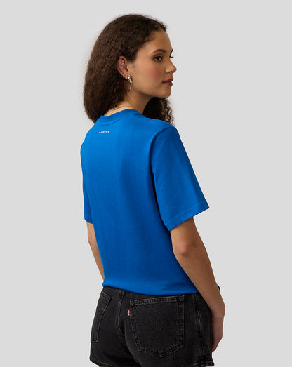 Back view of a lapis blue Alpine Core Essentials T-shirt worn by a woman, with a small Alpine logo on the upper back.