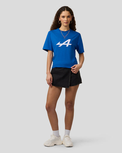 Front view of a woman in a lapis blue Alpine Core Essentials T-shirt with a large white graphic on the chest, paired with a black denim skirt.