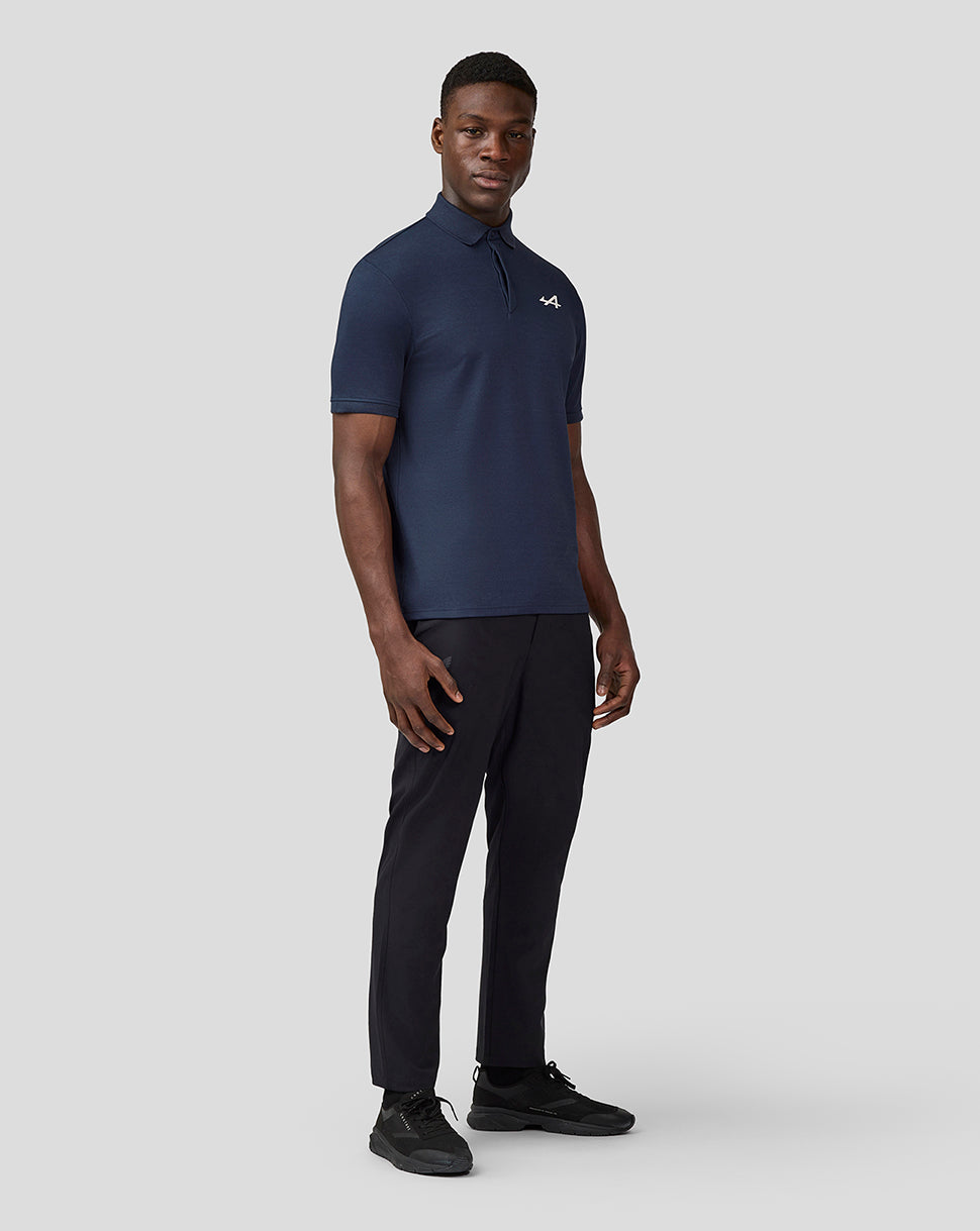 Male model in navy Alpine Core Essentials Polo Shirt with chest logo, paired with black trousers and sneakers.