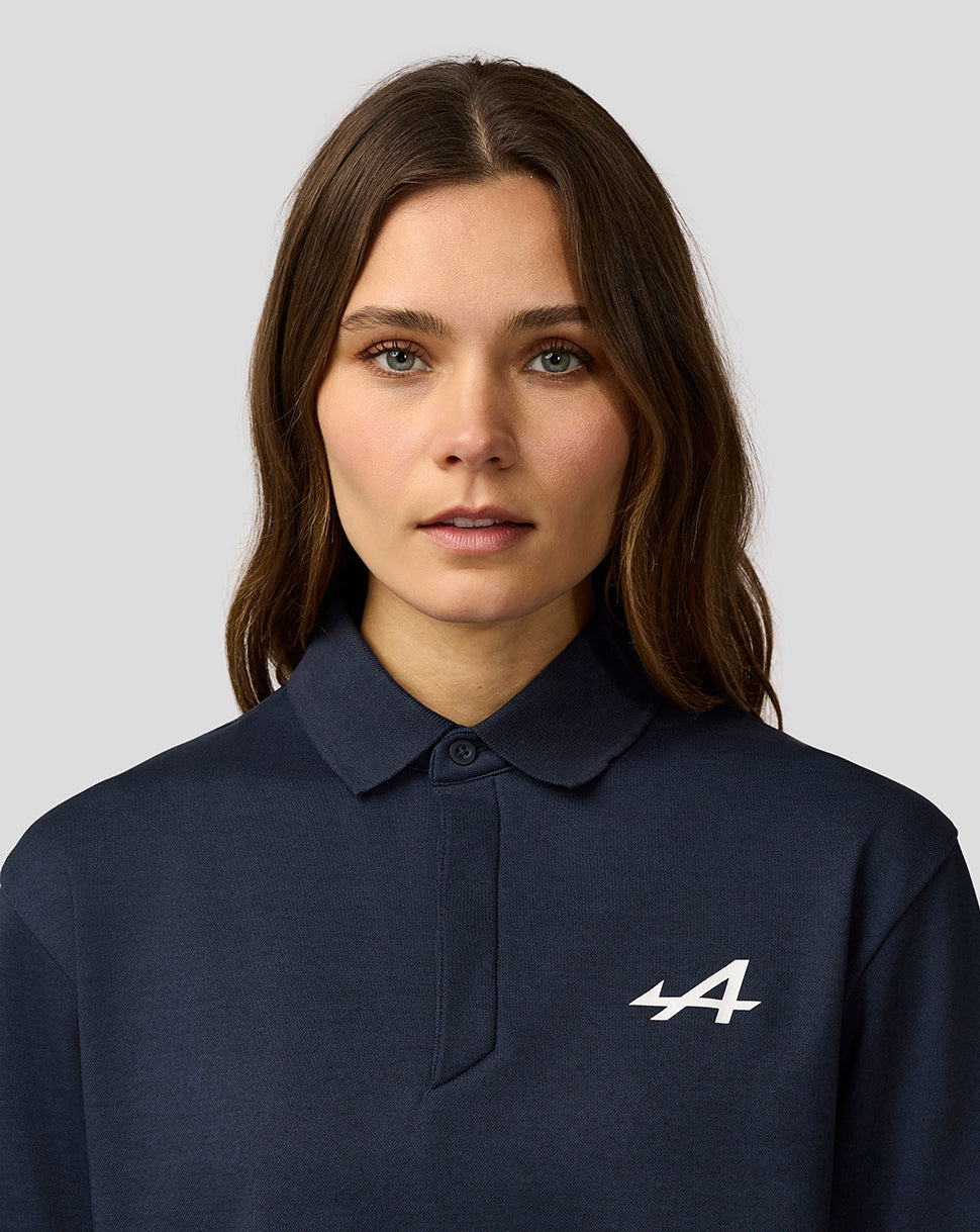 Female model wearing Alpine Core Essentials Polo Shirt in Black Iris with chest logo visible.