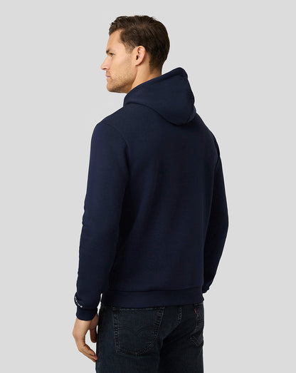 Back view of a model in navy Alpine Core Essentials Hoodie showing the hood and ribbed hem.