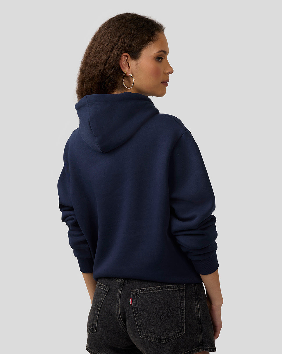 Back view of a model wearing a navy Alpine Core Essentials Hoodie with drawcord hood