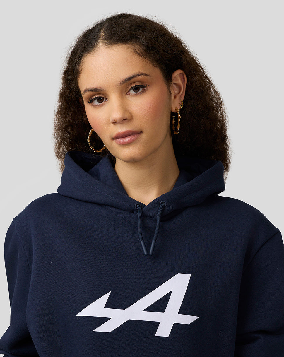 Portrait of a woman wearing a navy Alpine Core Essentials Hoodie with a bold front print and drawstring hood