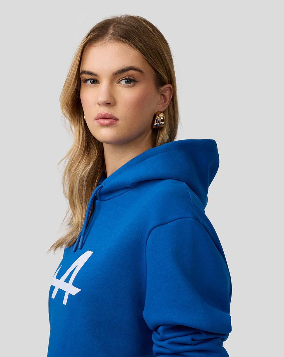 Female model in lapis blue Core Essentials Hoodie seen from the side with a bold white 44 logo on the chest