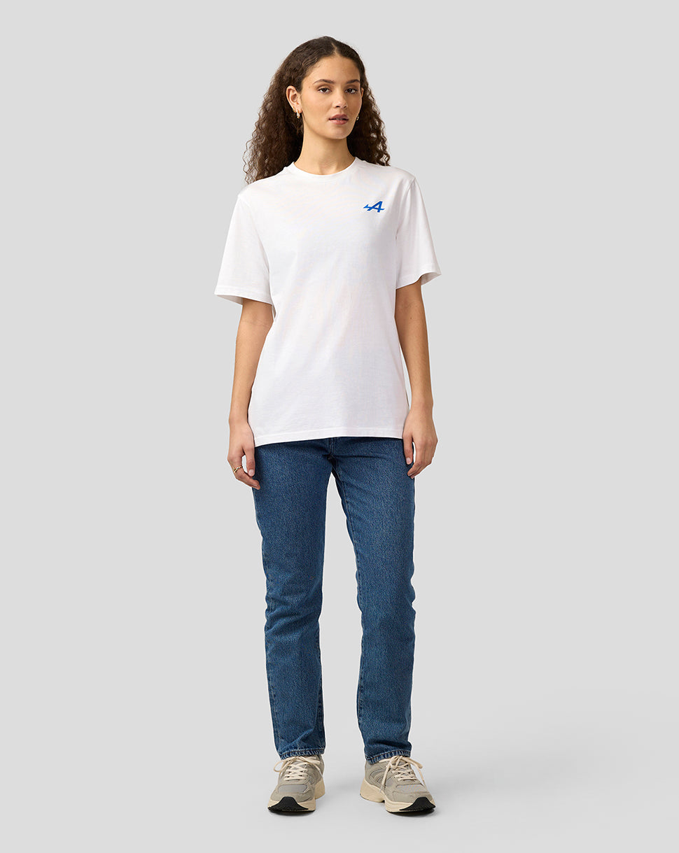 Full body view of a woman wearing a white Alpine Graphic T-Shirt with a blue logo on the chest