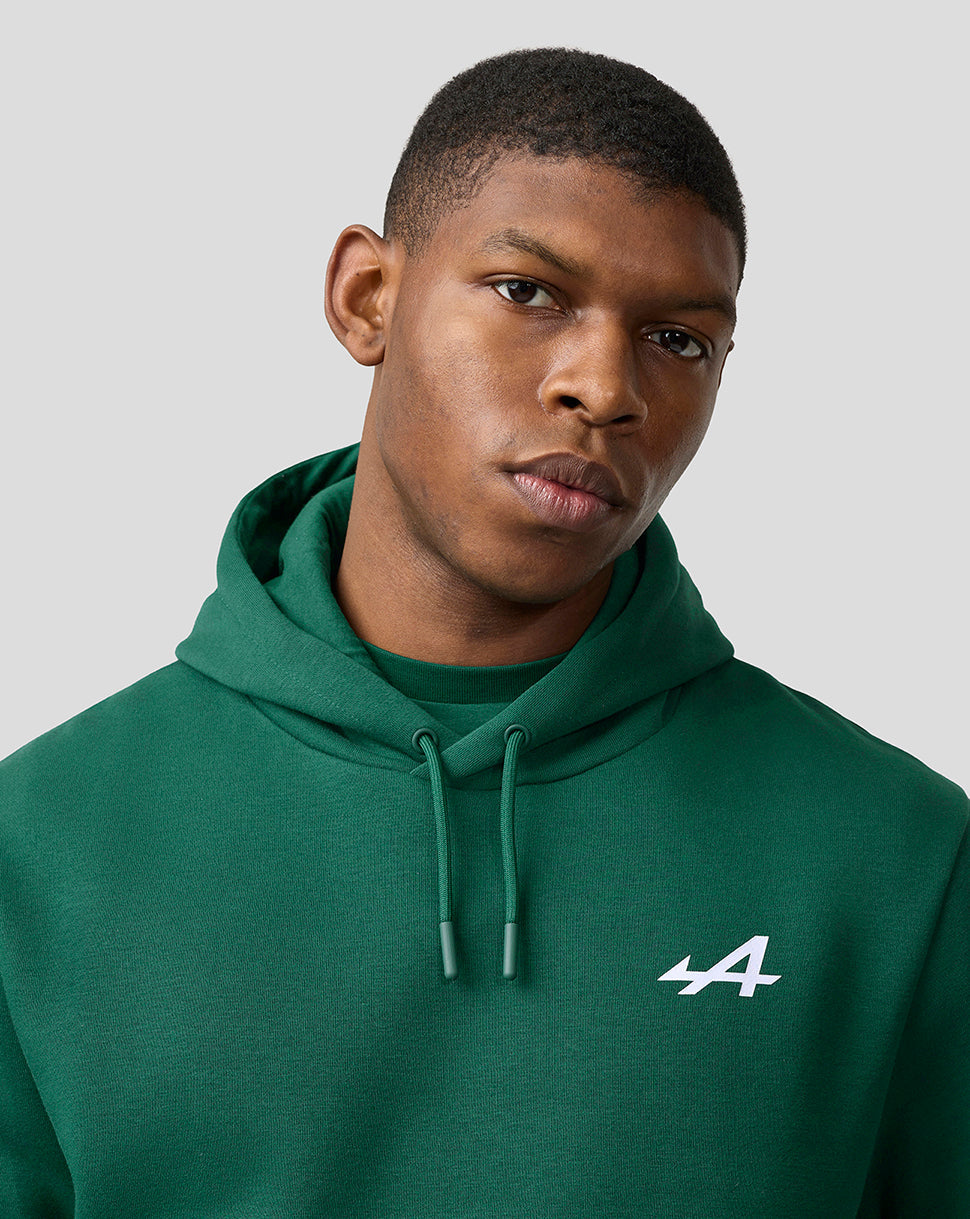 Close-up of male model wearing botanical green Alpine unisex hoodie with white logo on chest and drawstring hood