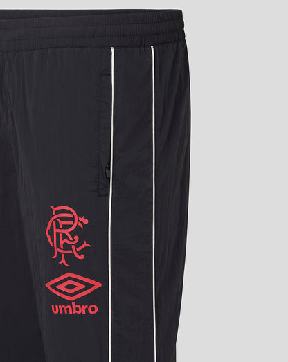Close-up of the pant leg showing white piping and red crest with Umbro logo on dark fabric