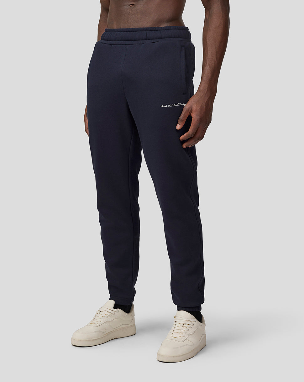 Front view of navy Oracle Red Bull Racing Heritage sweatpants on a model, featuring a drawcord waistband and cuffed ankles.