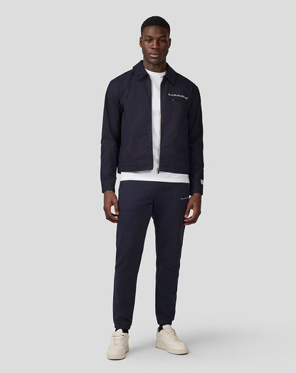 Full body shot of a male model in navy night sky cropped script work jacket with white tee and matching navy pants.