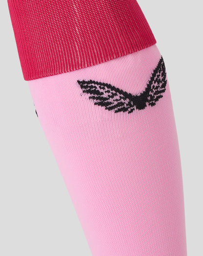 Close up of pink Harlequins Junior away sock showing red cuff and partial black emblem on the leg.