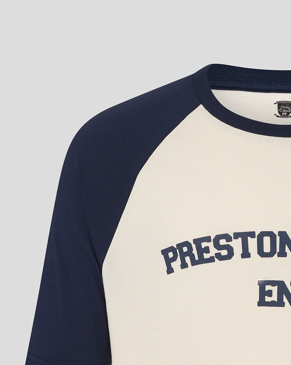 Close up at the neckline and shoulder showing navy sleeve on cream Preston raglan tee with partial text
