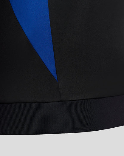 Close-up of the lower side showing a blue angular panel against black fabric and ribbed hem