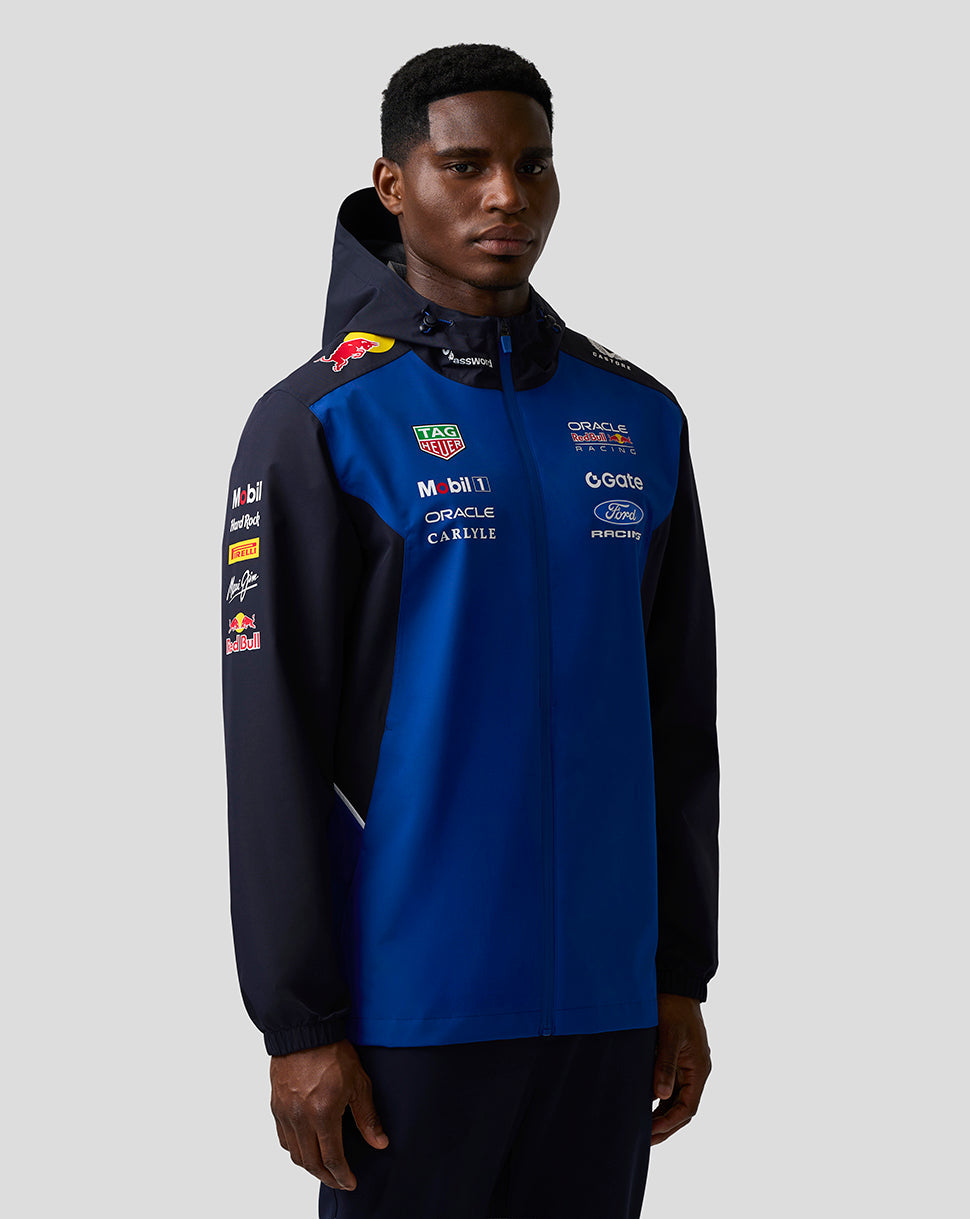 Front view of a model wearing a night sky blue and navy Teamline water resistant jacket with hood and sponsor branding.