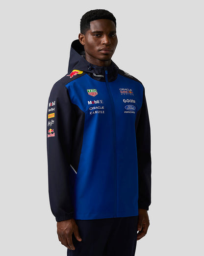 Front view of a model wearing a night sky blue and navy Teamline water resistant jacket with hood and sponsor branding.