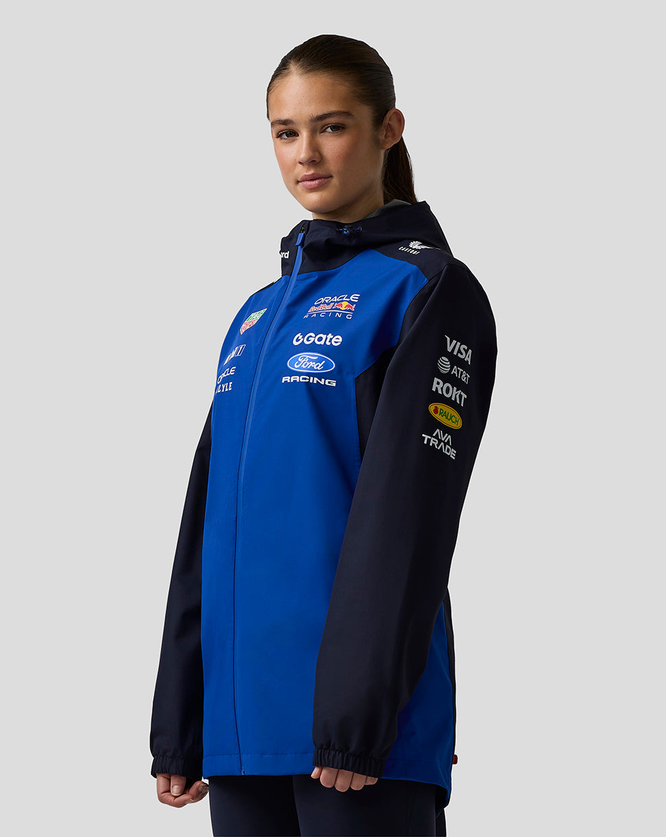 Model wearing blue and navy Oracle Red Bull Racing Teamline jacket with hood and branding on chest and sleeve.
