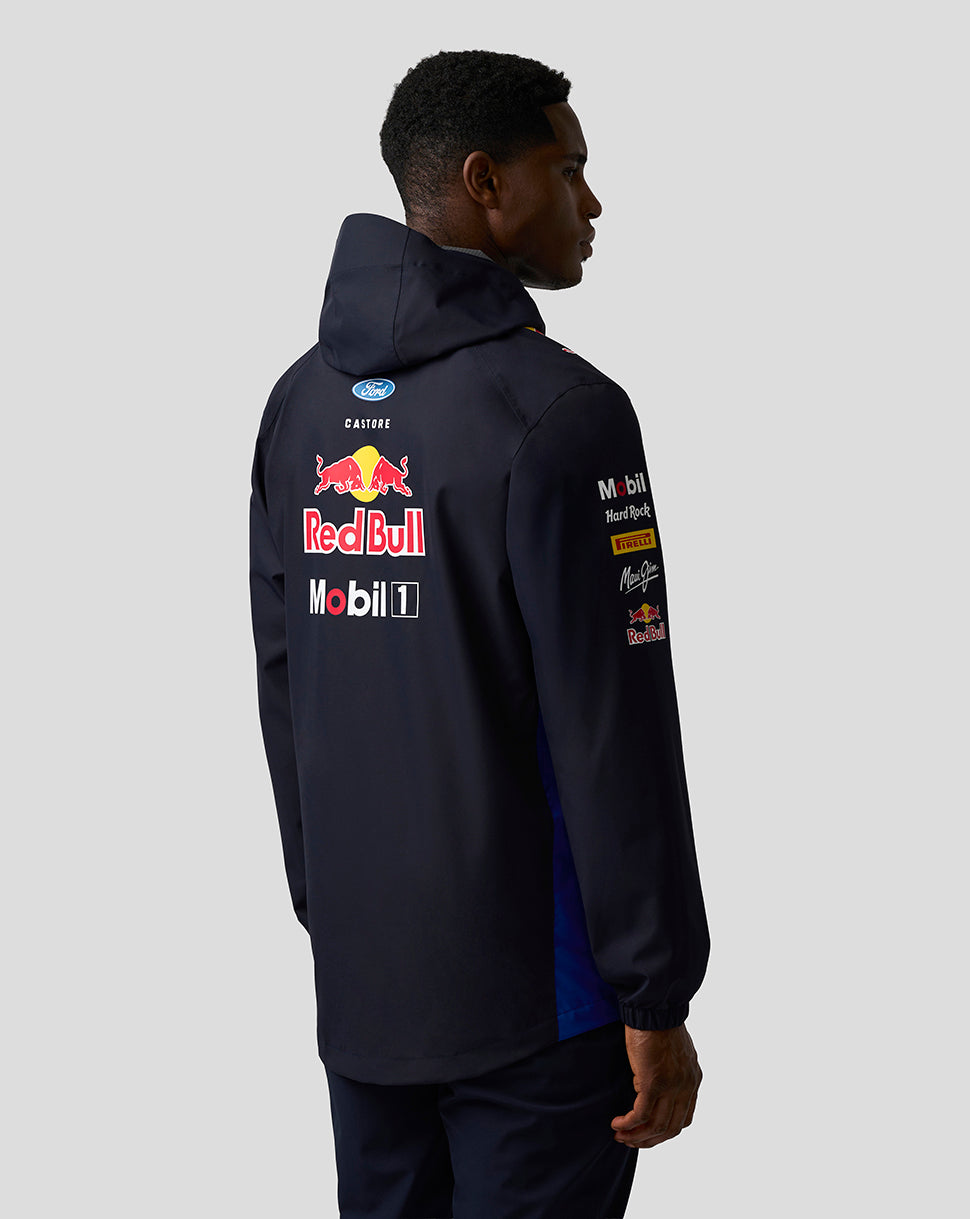 Back view of model in dark navy Red Bull Teamline jacket with prominent Red Bull and sponsor logos on the back.