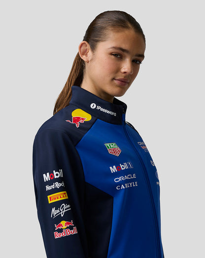 Female model wearing night sky blue Oracle Red Bull Racing Teamline Soft Shell Jacket with chest logos and zip collar