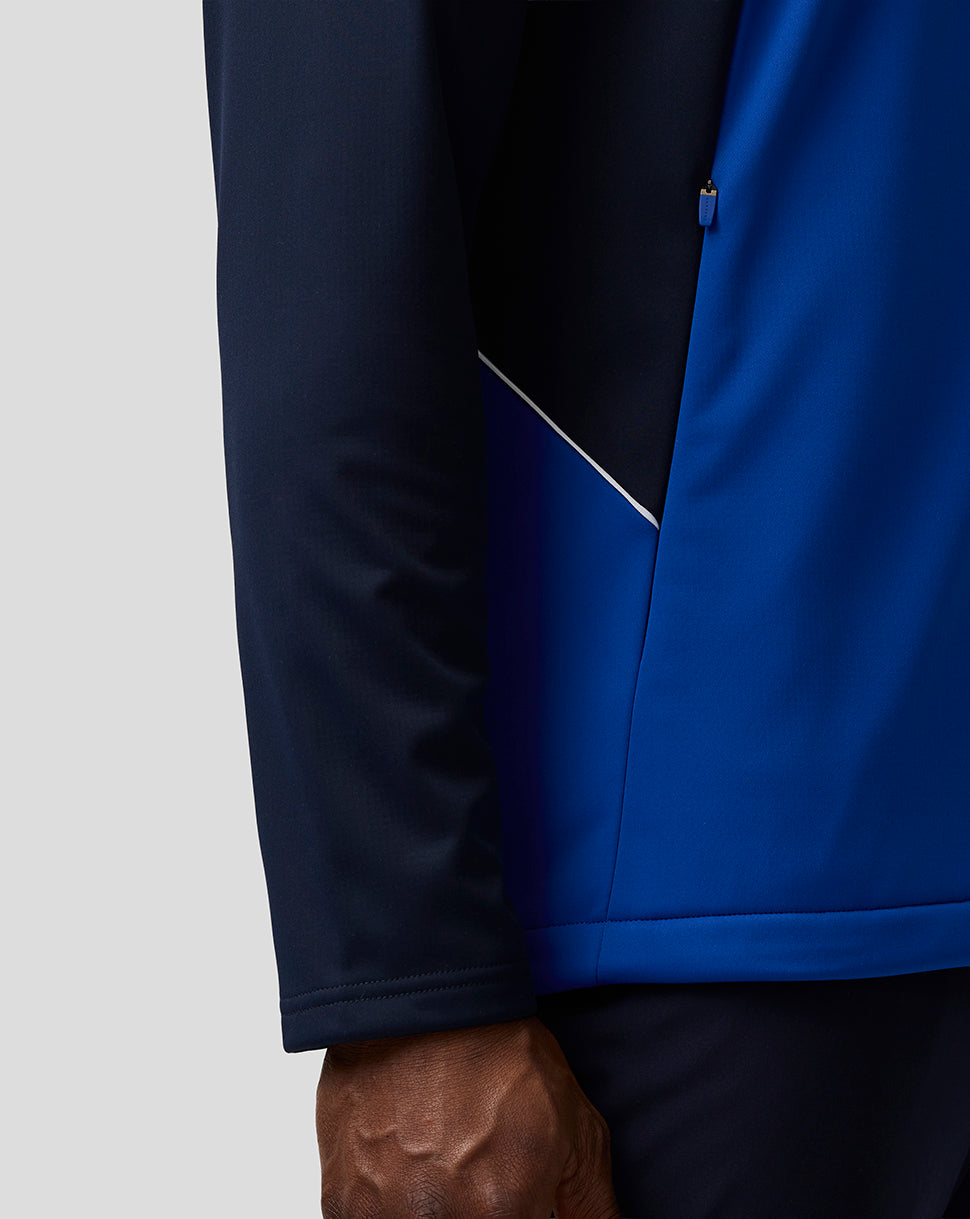 Close up of the Teamline jacket showing the navy sleeve and blue body with a side panel and white piping detail.
