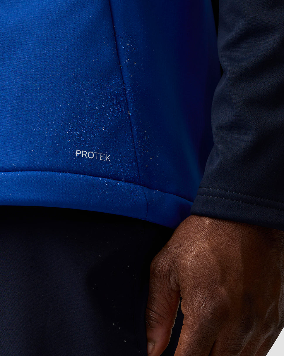 Close up of blue fabric with Protek label and water droplets beading on the surface.