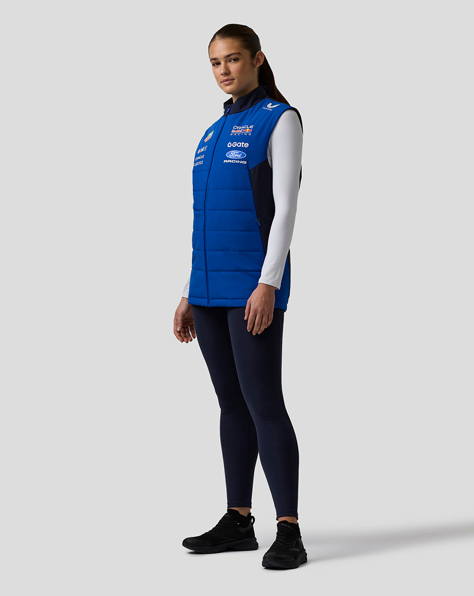 Profile view of a woman wearing a blue Oracle Red Bull Racing Teamline Gilet with sponsor branding.
