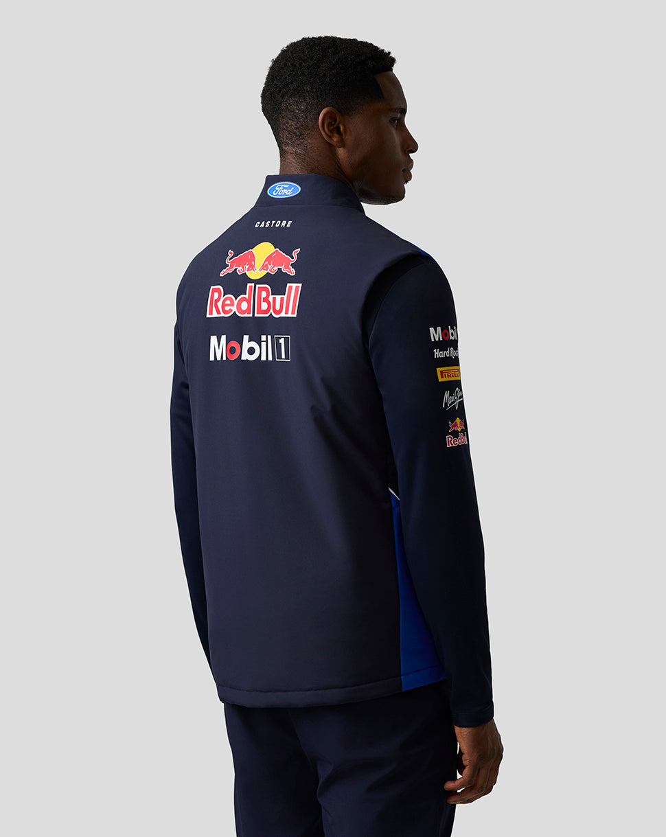 Back view of a man wearing a blue Teamline Gilet with a large Red Bull logo and sponsor branding.