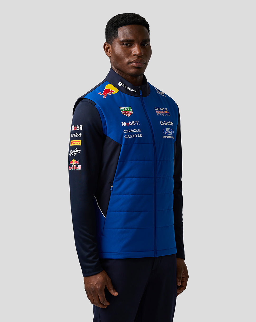 Male model in blue Teamline Gilet shown in profile with sponsor logos on the chest.