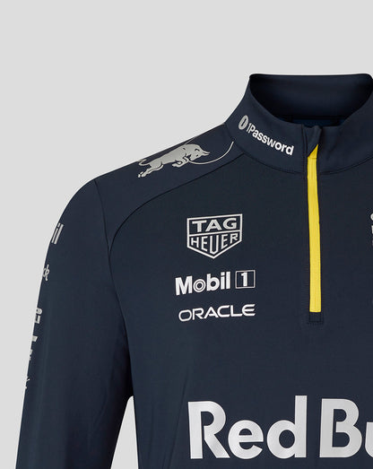 Shoulder and chest of navy team kit with a stand collar and yellow zipper displaying logos such as Tag Heuer Mobil 1 and Oracle.