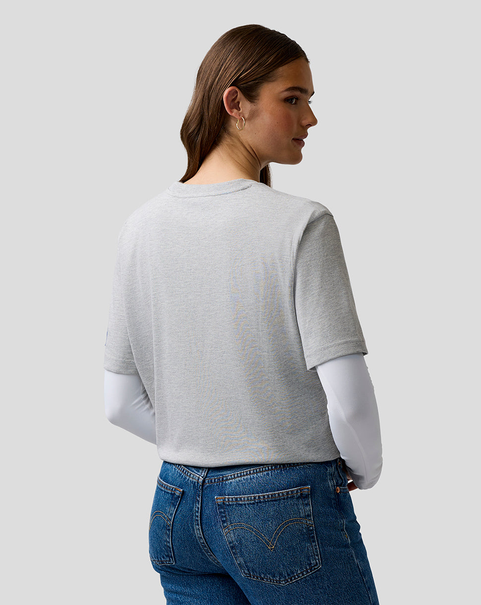 Woman wearing a gray cropped sweater and blue jeans on a plain background