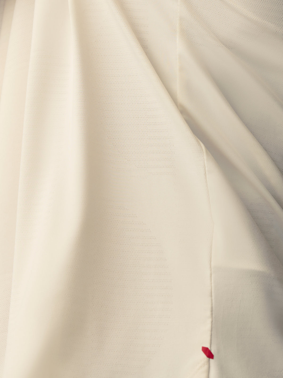 Close up of white knit T shirt showing Castore Paul Smith label sewn at the hem