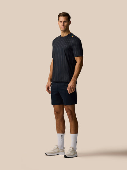 Full body side view of a male model in a dark pinstripe T-shirt with navy shorts and white socks