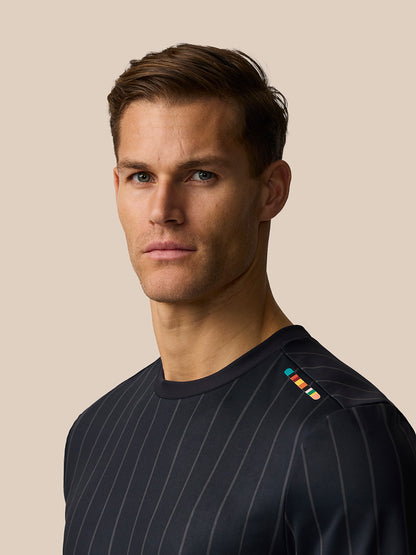 Male model wearing a dark navy striped Paul Smith x Castore England cricket T-shirt with the signature stripe on the front shoulder.