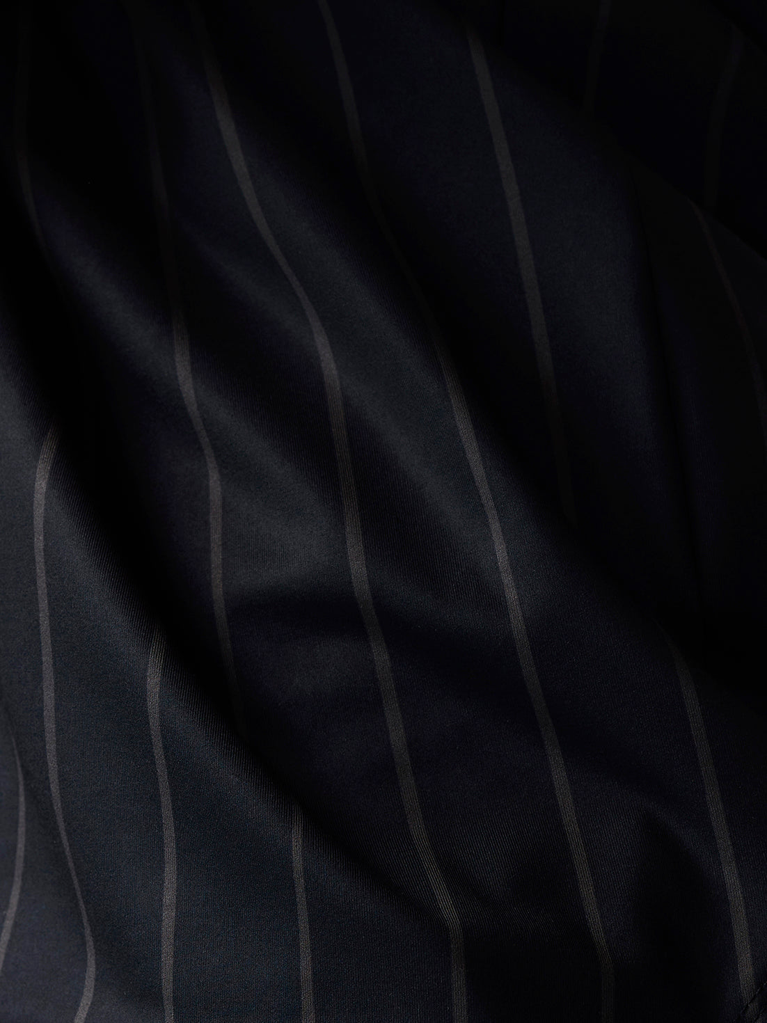 Close-up of the dark navy fabric with subtle vertical stripes from the Paul Smith x Castore T-shirt.