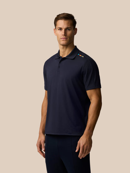 Full front view of navy Ashes polo paired with matching navy pants and sneakers shoulder stripe patch visible
