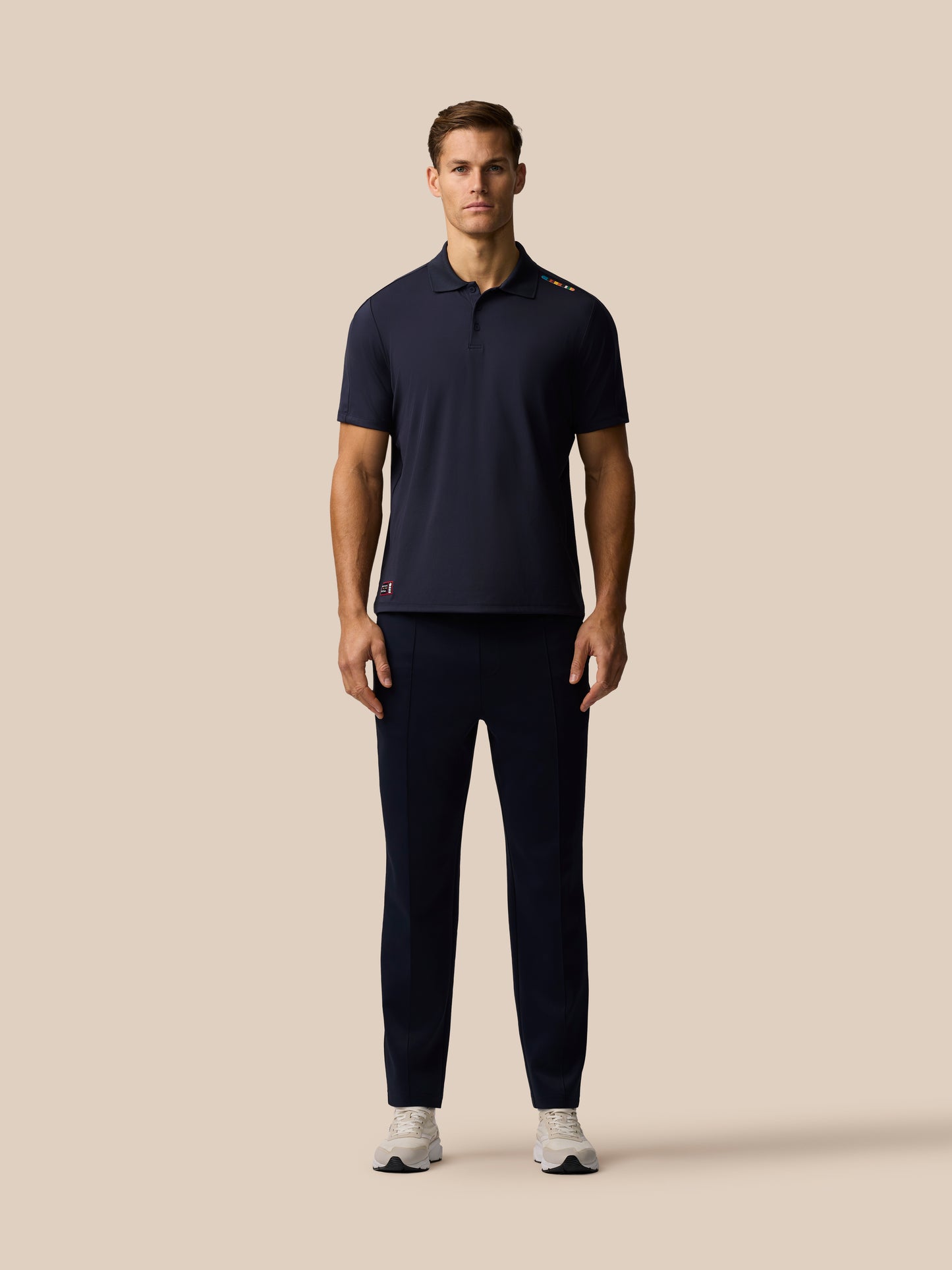 Front view of navy Paul Smith Castore ECB Ashes polo on a male model with colorful shoulder stripe