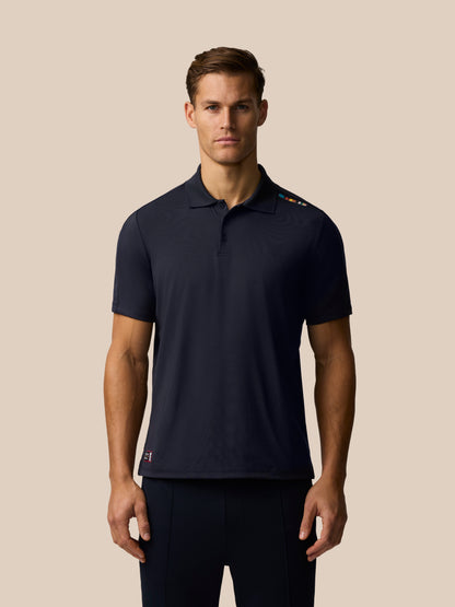 Male model wearing a navy Paul Smith x Castore England Cricket polo with signature shoulder stripe.