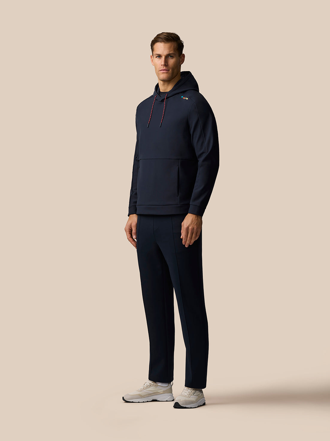 Model wearing navy Paul Smith Castore England Cricket hoodie with two piece hood red drawcords and signature stripe on the left shoulder