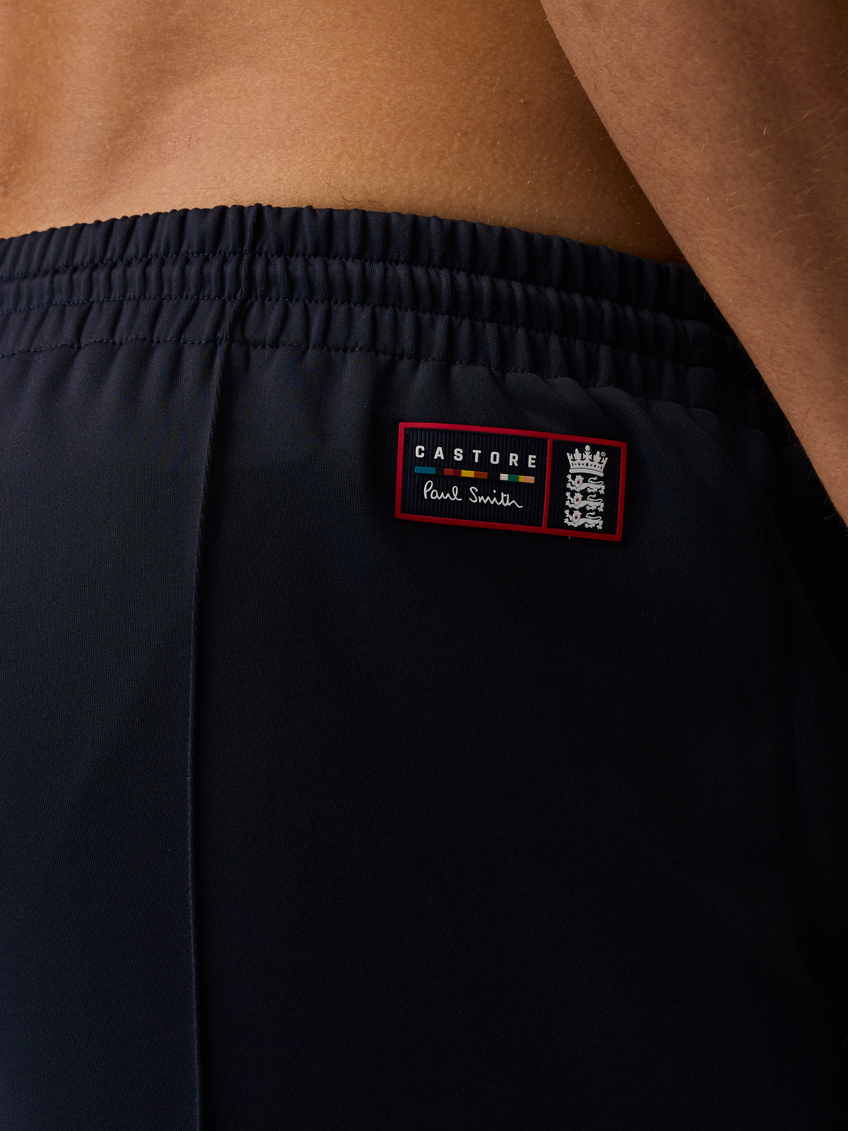 Close-up of navy unisex trousers waistband with elastic back and a Castore Paul Smith patch featuring the England crest.